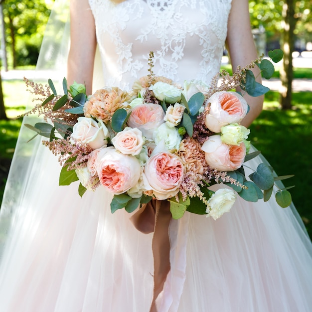 Braut, die draußen schönen großen Blumenstrauß von Rosen hält. Quadratischer Rahmen.