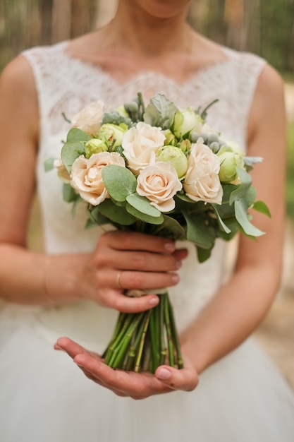 Braut, die einen Hochzeitsblumenstrauß in den Pastellrosafarben hält.