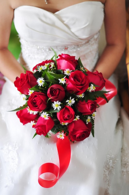 Braut, die roten Rosenblumenstrauß hält