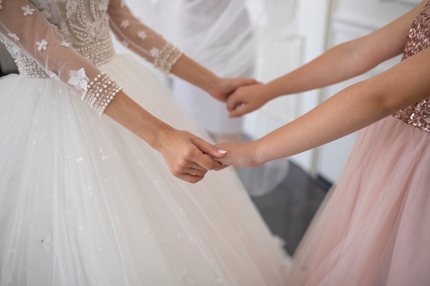 Foto braut hält hände mit ihrer freundin am hochzeitstag.