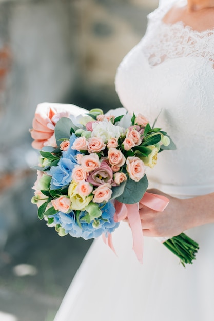 Braut im weißen Kleid, das schönen Blumenstrauß hält