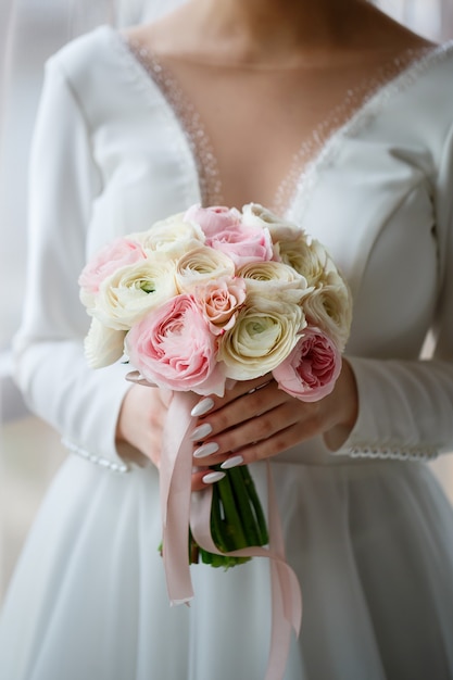 Braut im weißen Kleid hält einen Blumenstrauß