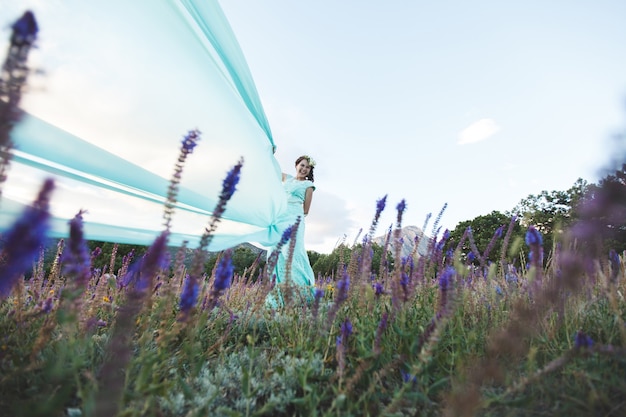 Braut in der Natur in den Bergen in der Nähe des Wassers. Kleiderfarbe Tiffany. Die Braut spielt mit seinem Kleid.