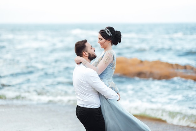 Braut in einem blauen Kleid geht am Meer entlang