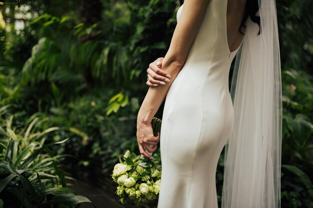 Braut in einem eleganten sexy Kleid mit einem Blumenstrauß