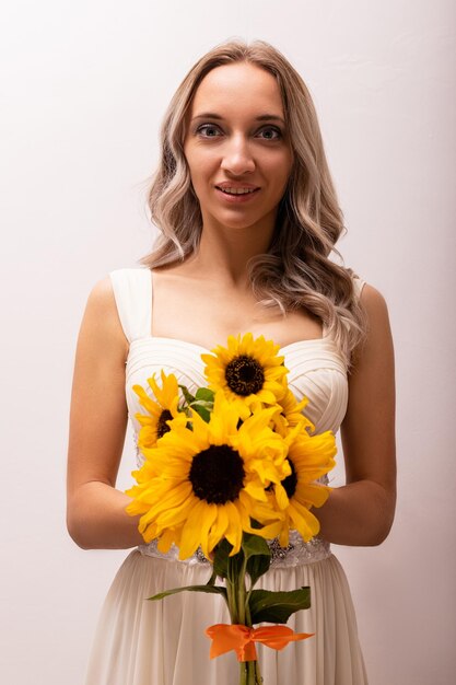 Braut in einem Hochzeitskleid mit einem Sonnenblumenstrauß Schöne FrauFloristik