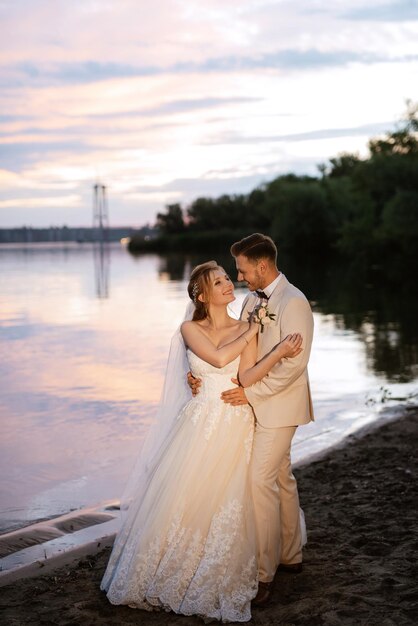 Braut in einem weißen, bauschigen Kleid und der Bräutigam in t am Flussufer