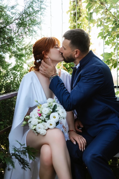 Braut in einem weißen Kleid mit Blumenstrauß und der Bräutigam in einem blauen Anzug