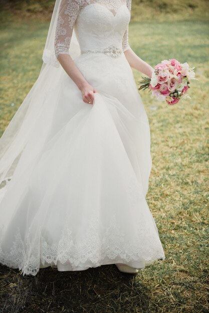 Braut in einem weißen Kleid mit einem rosa Blumenstrauß. Hochzeit im Frühling