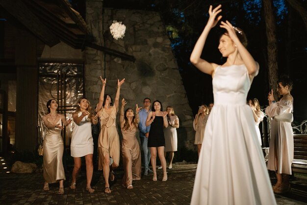 Braut in einem weißen Kleid wirft einen Hochzeitsbouquet