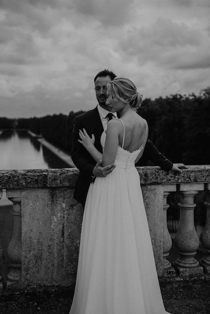 Braut in einem wunderschönen Hochzeitskleid, Bräutigam in einem stilvollen Smoking, gehen Sie zum alten Schloss in Frankreich