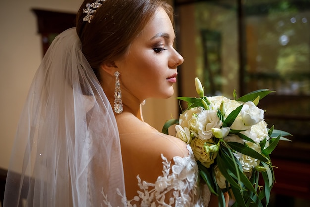 Braut in einem wunderschönen weißen Kleid am Hochzeitstag mit einem Blumenstrauß in den Händen