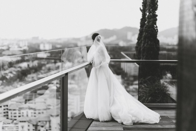 Braut in Hochzeitskleidung steht auf der Terrasse des Gebäudes