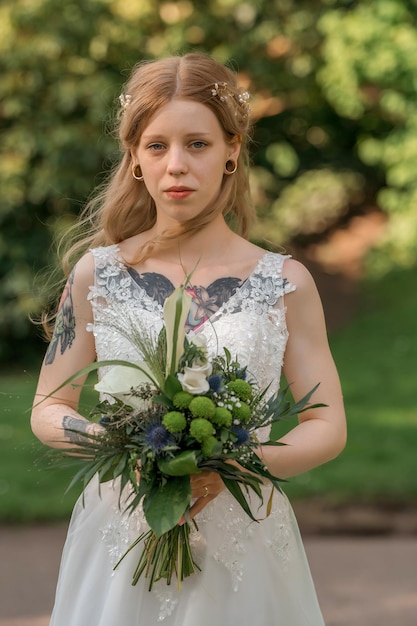 Braut mit einem Blumenstrauß bis zum Hals, Fokus auf Blumen. Tätowierte Braut