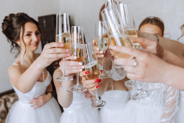 Braut mit fröhlichen Freundinnen auf der Hochzeit trinken Champagner aus Gläsern Braut und Freundinnen