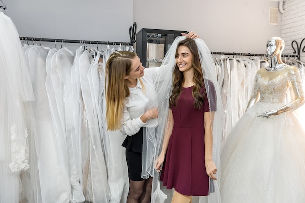 Braut mit Schneider, die Hochzeitskleid im Geschäft wählt