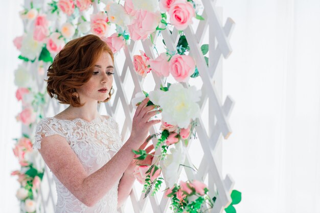 Braut steht eine Wand mit Rosen