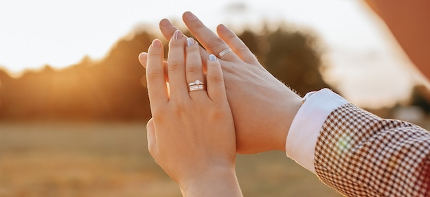 Braut und Bräutigam am Hochzeitstag umarmen und sehen Ringe bei Sonnenuntergang