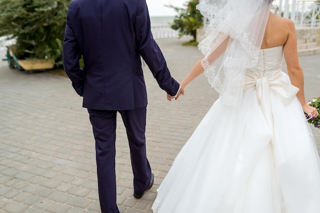 Braut und Bräutigam am Hochzeitstag zu Fuß im Freien Brautpaar Happy Newlywed Frau und Mann-Konzept Liebevolle Hochzeit Nahaufnahme