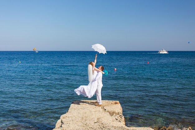 Braut und Bräutigam am Meer an ihrem Hochzeitstag.