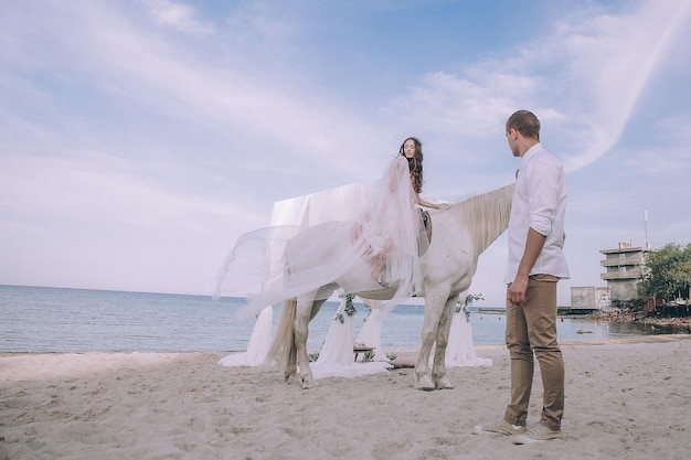 Foto braut und bräutigam am strand mit pferden. brautpaar. schönes portrait in der natur