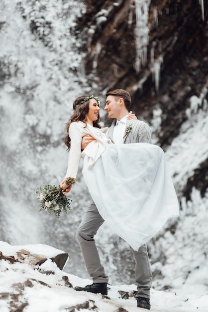 Braut und Bräutigam an der Wand eines Bergwasserfalls