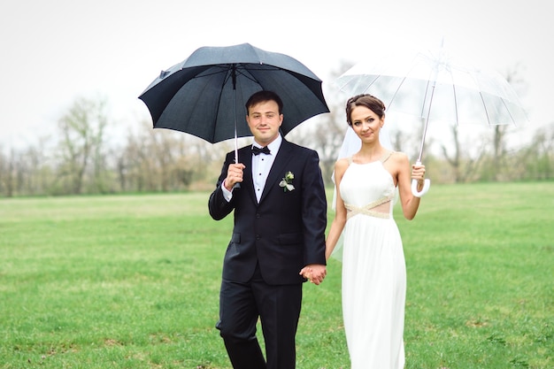 Braut und Bräutigam an einem regnerischen Hochzeitstag unter einem Regenschirm