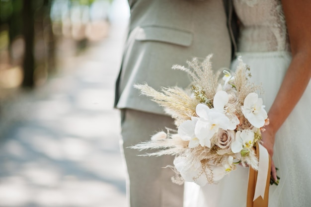 Braut und Bräutigam, die schönen zarten Hochzeitsblumenstrauß halten