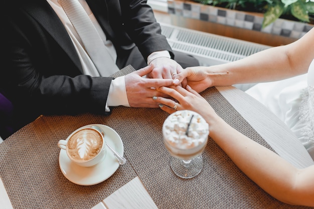 Braut und Bräutigam Händchen haltend. Ein romantischer Moment. Cappuccino und Latte mit Marshmallows.