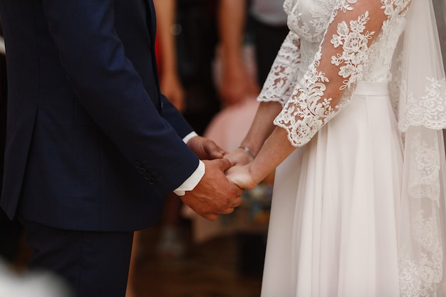Braut und Bräutigam halten sanft die Hände in der Nähe. Hochzeitstag.