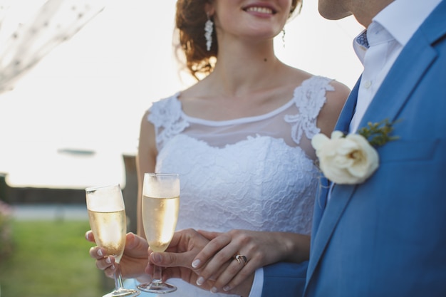 Braut und Bräutigam halten schön dekorierte Hochzeitsgläser mit Champagner
