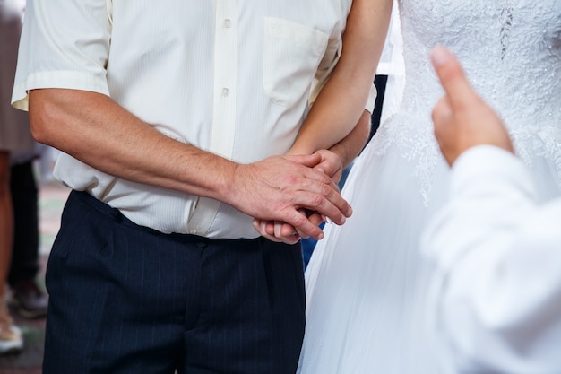 Braut und Bräutigam halten sich am Hochzeitstag an den Händen