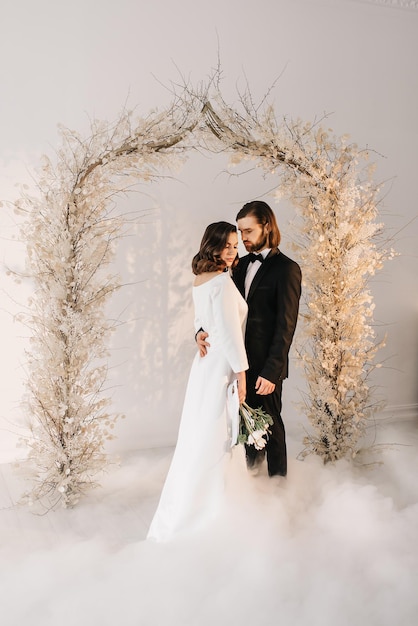 braut und bräutigam in hochzeitskleidern in einem hellen innenraum am hochzeitstag familienporträt