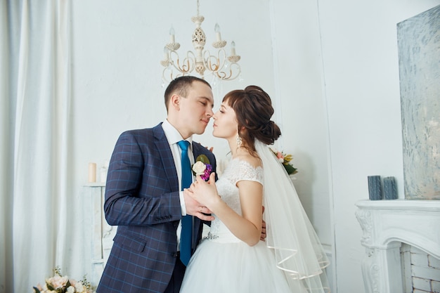 Braut und Bräutigam in Hochzeitskleidern umarmen sich zu Hause. Verliebtes Paar nach einer Hochzeitszeremonie