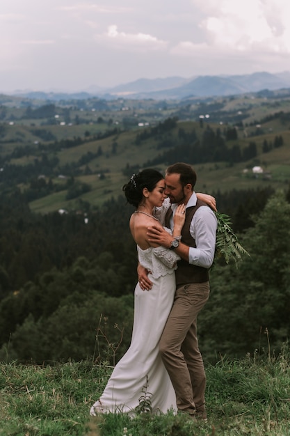 Braut und Bräutigam küssen sich in den Bergen