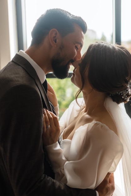 Braut und Bräutigam küssen sich vor einem Fenster