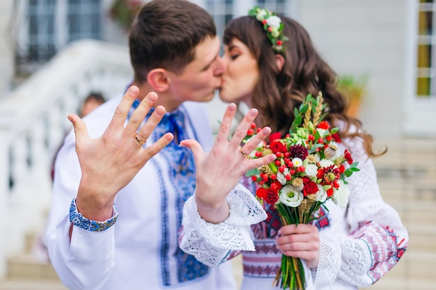 Braut und Bräutigam küssen und zeigen Hände mit Eheringen an einem Ringfinger