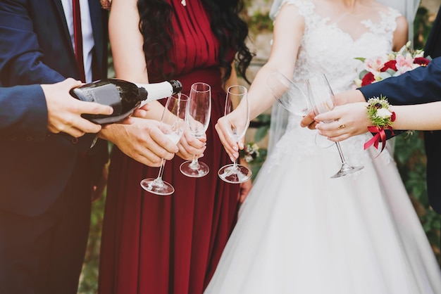 Braut und Bräutigam mit den besten Freunden, die einen Champagner trinken, Nahaufnahme