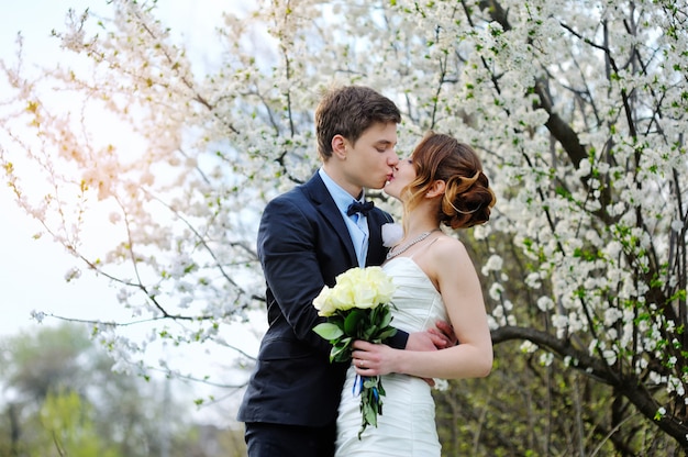 Braut und Bräutigam mit einem Blumenstrauß des Gehens in den Sommerpark