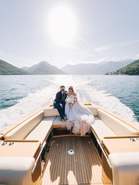 Foto braut und bräutigam mit sonnenbrille sitzen auf einer yacht, die auf dem meer segelt