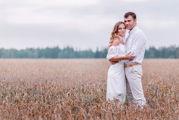 Braut und Bräutigam posieren auf einem Weizenfeld