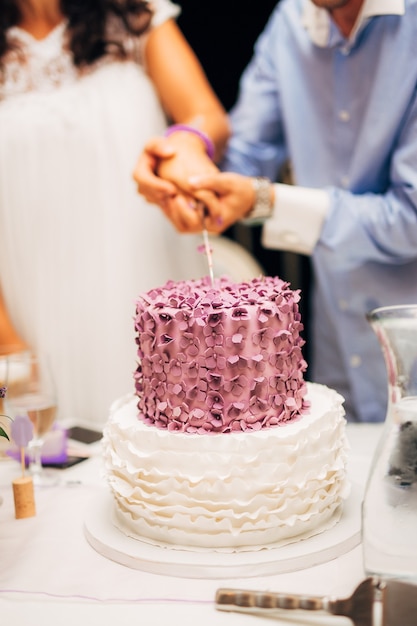 Braut und Bräutigam schneiden die Hochzeitstorte