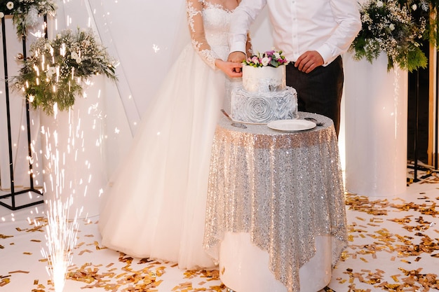 Braut und Bräutigam schneiden ihre rustikale Hochzeitstorte auf Hochzeitsbankett Hände schneiden den Kuchen mit zarten rosa Blüten