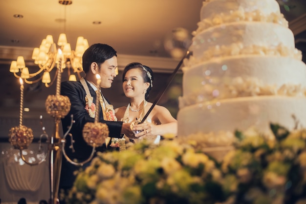 Braut und Bräutigam schneiden Kuchen für die Feier an ihrem Hochzeitstag