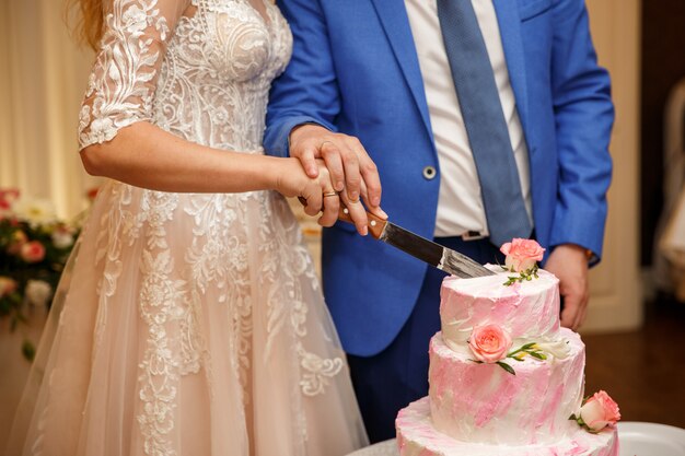 Braut und Bräutigam schneiden rosa Hochzeitstorte