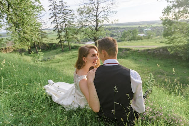 Braut und Bräutigam sitzen im grünen Gras.