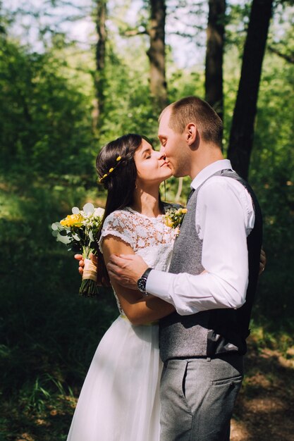Braut und Bräutigam umarmen am Hochzeitstag, glückliches junges Paar, das im Park in der Natur, Valentinstag küsst