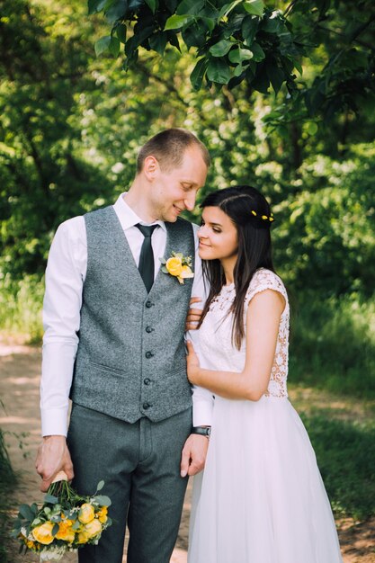 Braut und Bräutigam umarmen am Hochzeitstag, glückliches junges Paar, das im Park in der Natur, Valentinstag küsst