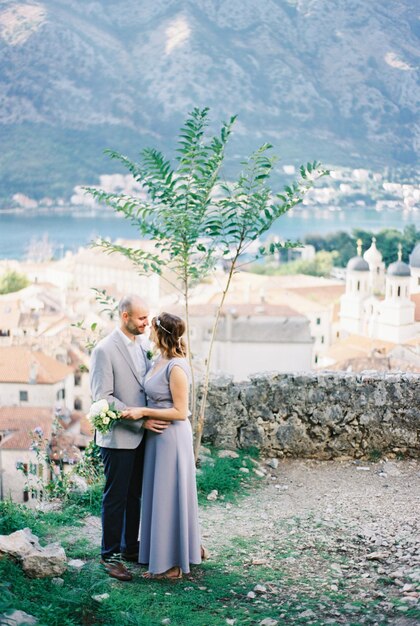 Braut und Bräutigam umarmen sich auf der Aussichtsplattform über den Häusern von Kotor Montenegro