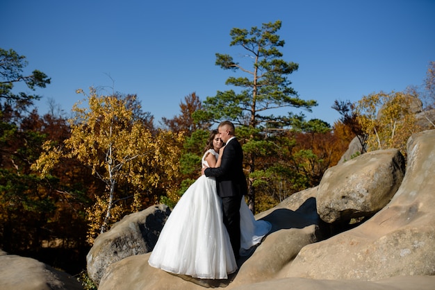Braut und Bräutigam umarmen sich auf einer Klippe